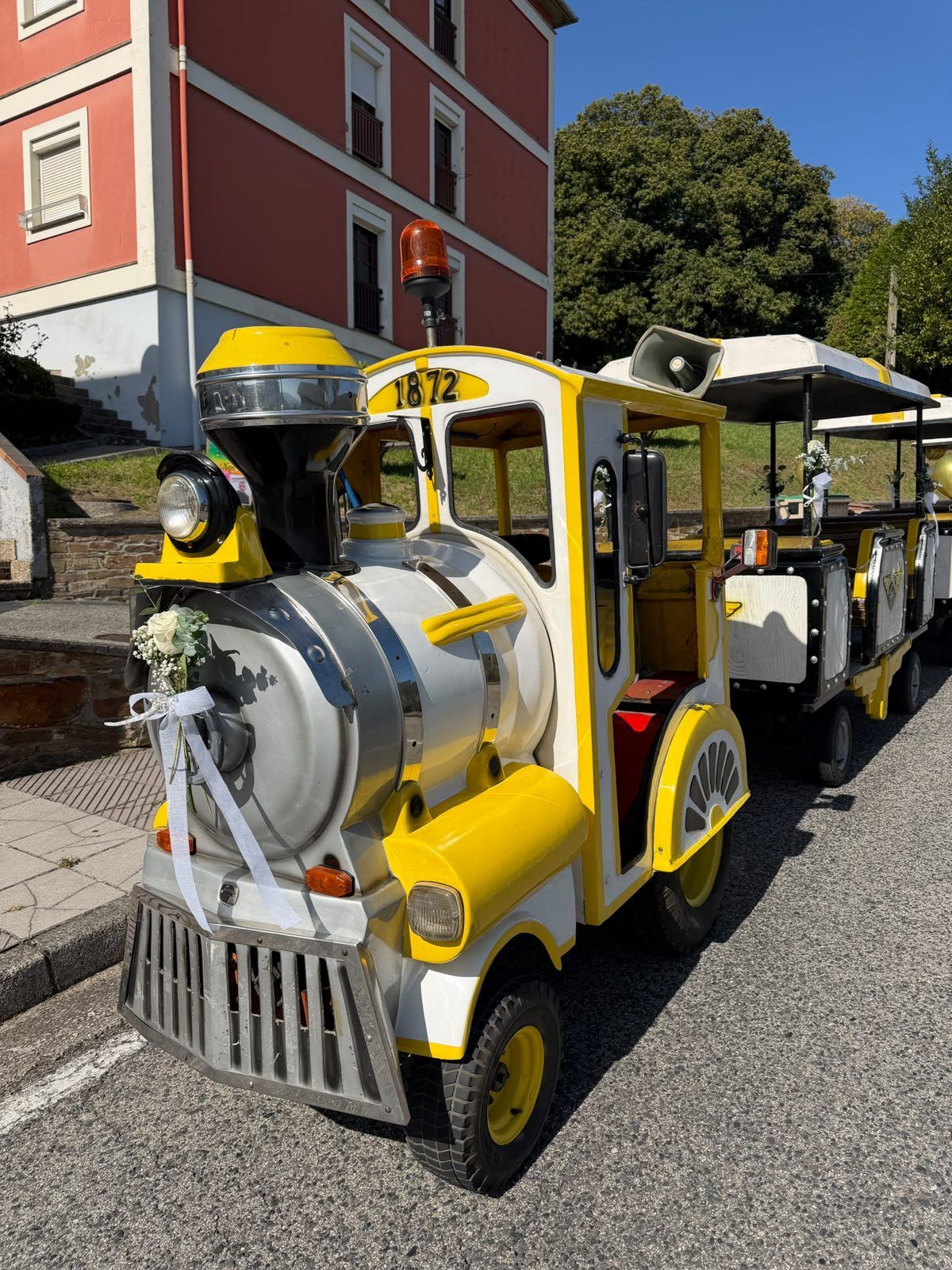 Trenecito turístico decorado con flores y lazos para el transporte de invitados de boda